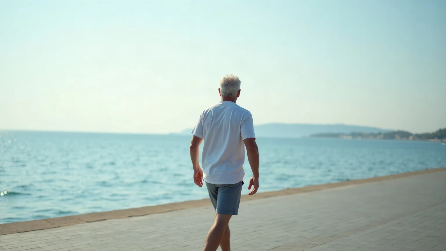 Άνδρας περπατά ήρεμα σε παραλιακό πεζόδρομο, εικόνα της ζωής μετά το ανεύρυσμα εγκεφάλου
